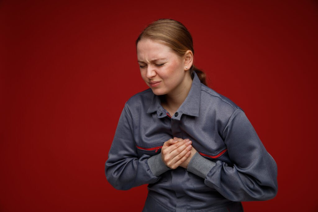 Aching Young Blonde Female Engineer Wearing Uniform Keeping Hands On Chest With Closed Eyes Isolated On Bordo Background With Copy Space